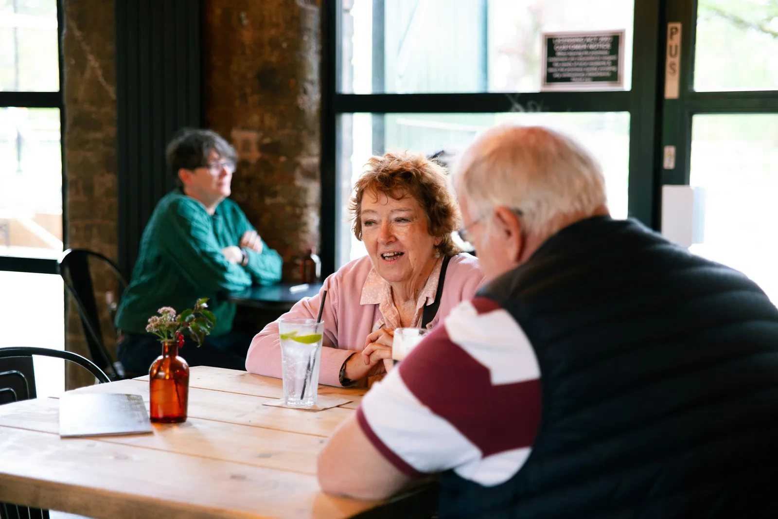 An older woman laughing in conversation with a friend at a cafe table
