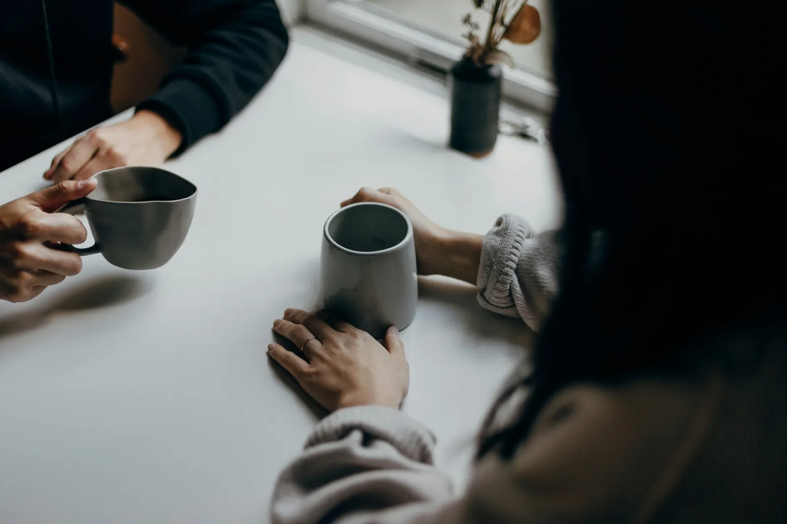 Two people talking over coffee at a table.